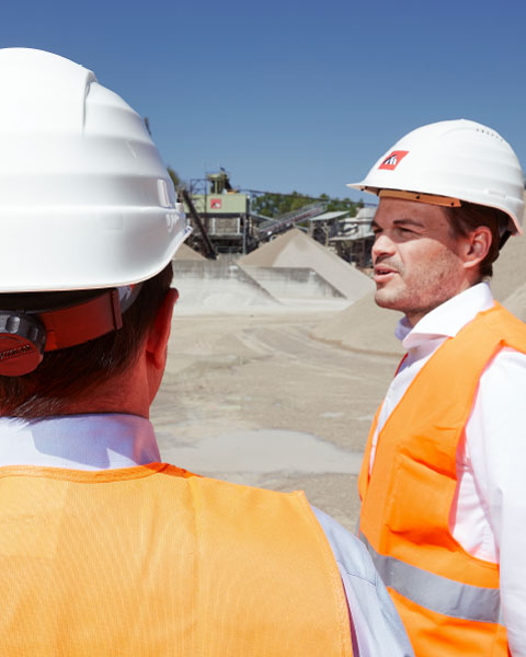 Zwei Arbeiter mit Helm besprechen auf der Baustelle die Lage